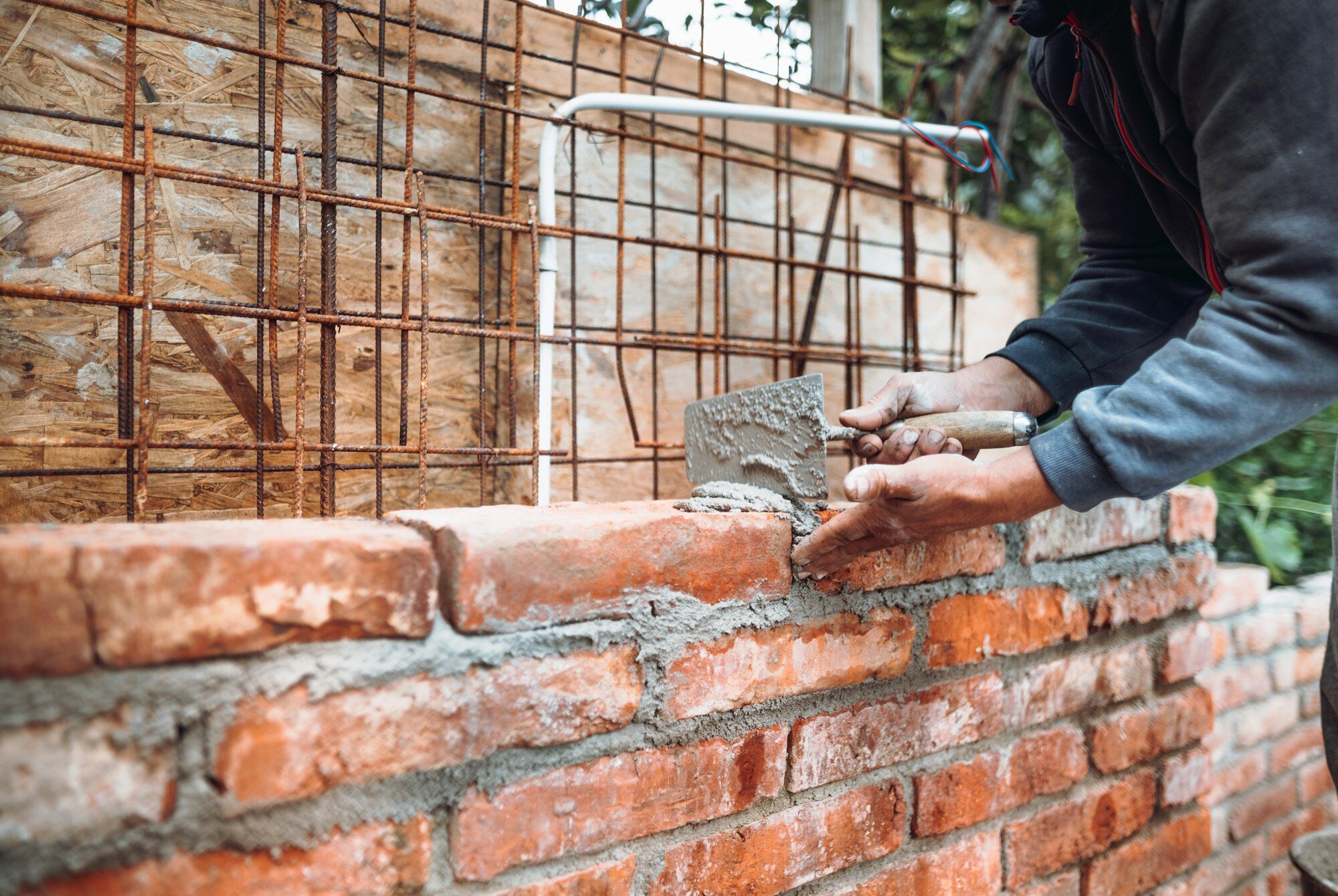 Construction bricklayer worker building brick walls with mortar, trowel. Industry details